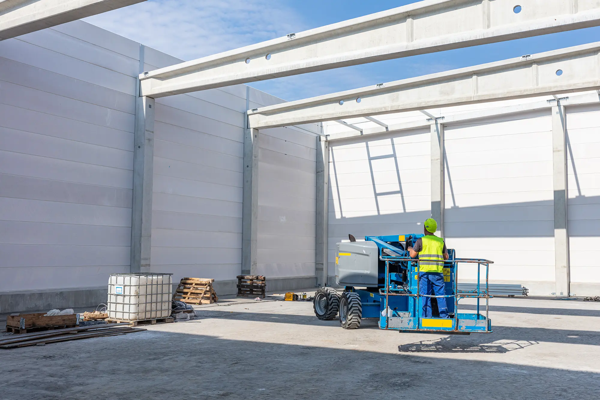 Cold storage construction worker installing insulated metal panels from elevated lift